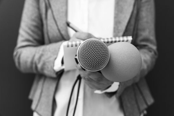 Reporter på presskonferens, skriver anteckningar, håller mikrofon. Mediehändelse.